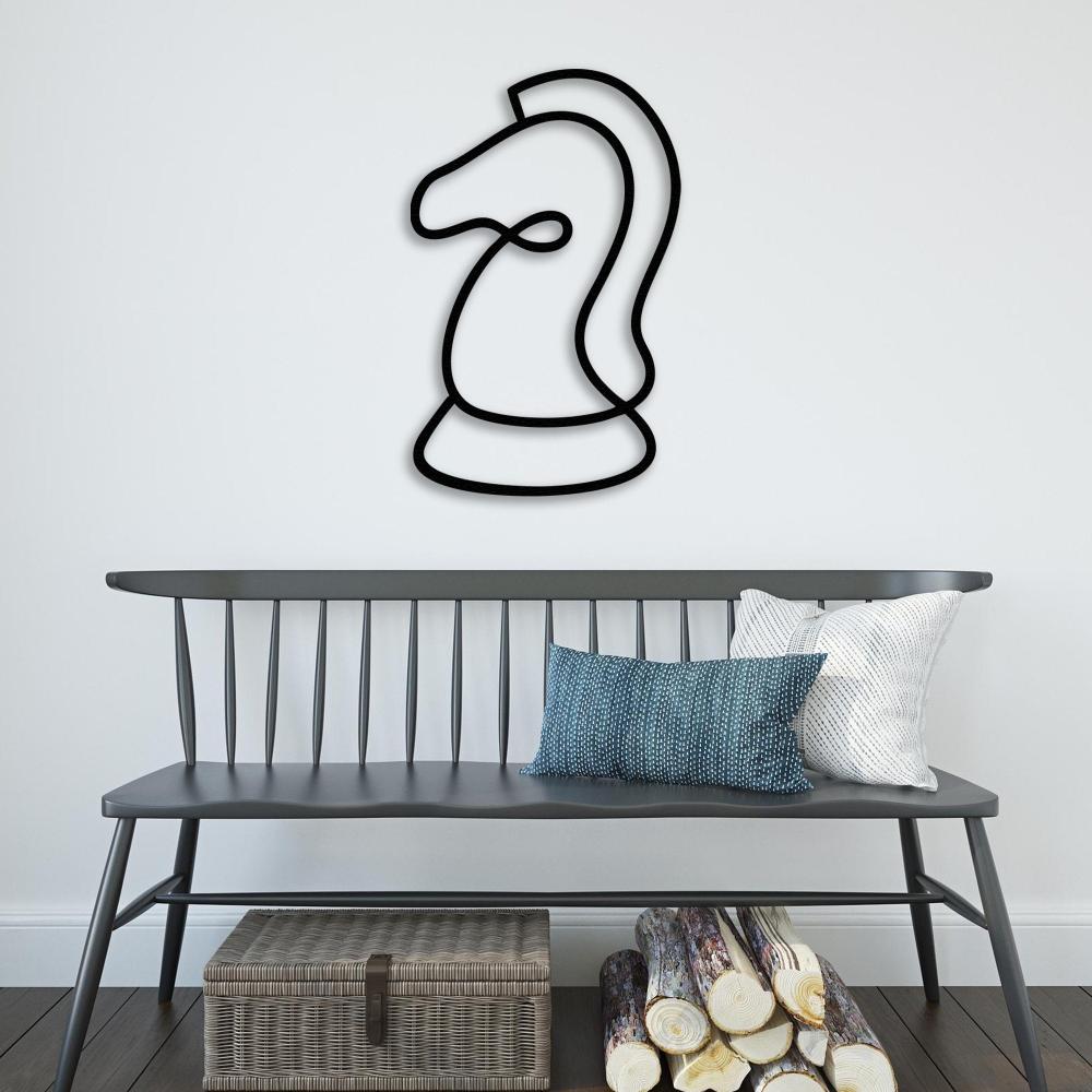 Black chess knight metal wall art displayed above a gray bench with pillows and firewood stacked below, creating a cozy entryway decor. 