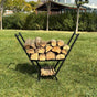 A black minimalist V-shaped metal wood holder displayed indoors next to a fireplace, holding stacked firewood with an additional compartment for kindling below.