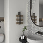 A bathroom featuring a minimalist vertical towel rack in matte black holding neatly rolled towels, mounted beside a round mirror with patterned tiles, creating a stylish and functional design.