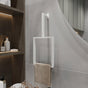 A minimalist white-finished vertical towel ring is mounted on a light gray wall. The modern rectangular design holds a beige towel, adding a clean and stylish touch to the bathroom decor. The sleek towel ring enhances the minimalist aesthetic of the space, perfectly complementing the surrounding neutral tones and simple design elements.