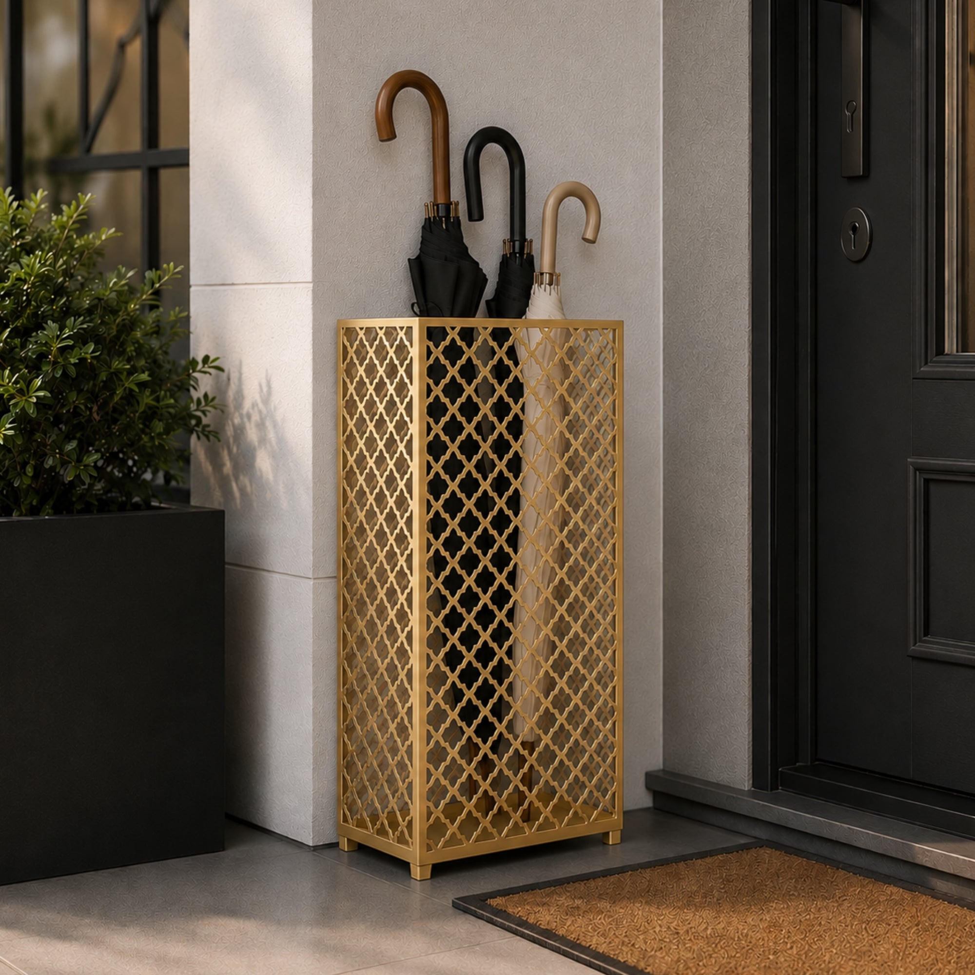 Gold mesh metal umbrella stand at modern front door entrance with olive plant and stone planter decor