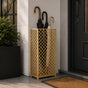 Gold mesh metal umbrella stand at modern front door entrance with olive plant and stone planter decor