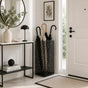 Black mesh metal umbrella stand in bright entryway with mirror and minimalist Scandinavian decor