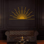 Gold minimalist sunburst metal wall art with a sunrise design mounted on a dark wall, complementing a luxurious black leather tufted sofa and a sleek glass coffee table.