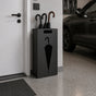 Black metal umbrella stand with umbrella cutout design in modern garage entryway holding multiple umbrellas