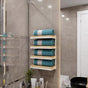 Modern bathroom featuring a chic wall-mounted towel rack with light wood shelves. The compact design holds rolled towels neatly, adding both functionality and a touch of natural warmth to the sleek, tiled space.