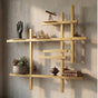 Gold modular metal wall shelf with books, plants, and decorative objects on a textured wall.