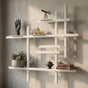 White modular metal wall shelf with books, plants, and decorative objects on a textured wall.