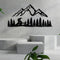 Black metal wall art featuring a scenic mountain range and dense pine forest, with a winding road leading through the trees, mounted on a neutral concrete backdrop for a modern, nature-inspired decor theme.
