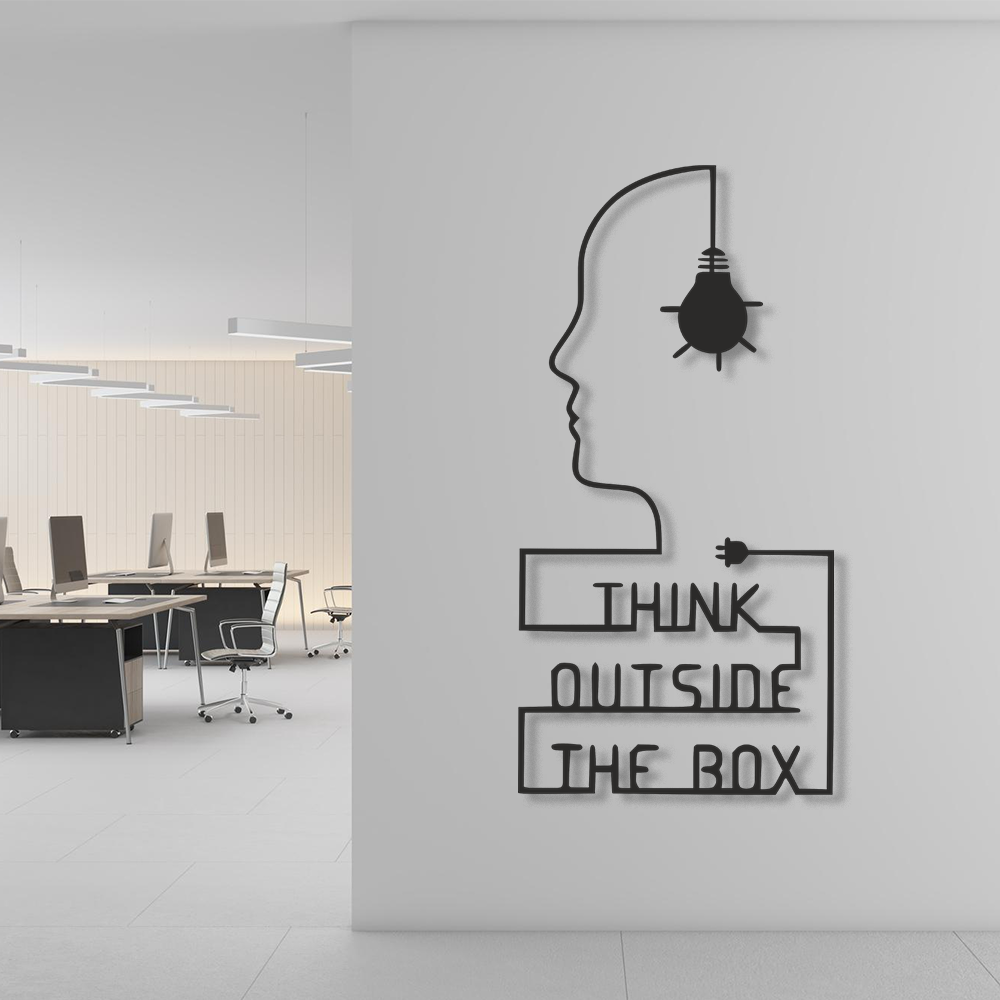 Decorative wall art with a silhouette of a head, light bulb, and text 'Think Outside the Box' in an office setting.
