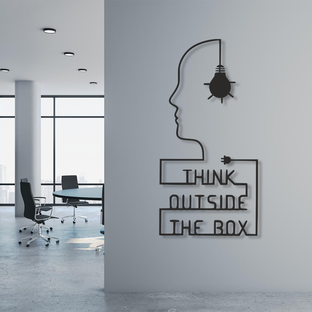 Modern office interior with a wall decoration featuring a silhouette of a head and light bulb, accompanied by the text 'Think Outside The Box'.