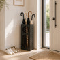 Contemporary black metal umbrella stand with oval mesh portholes in modern entryway with umbrellas