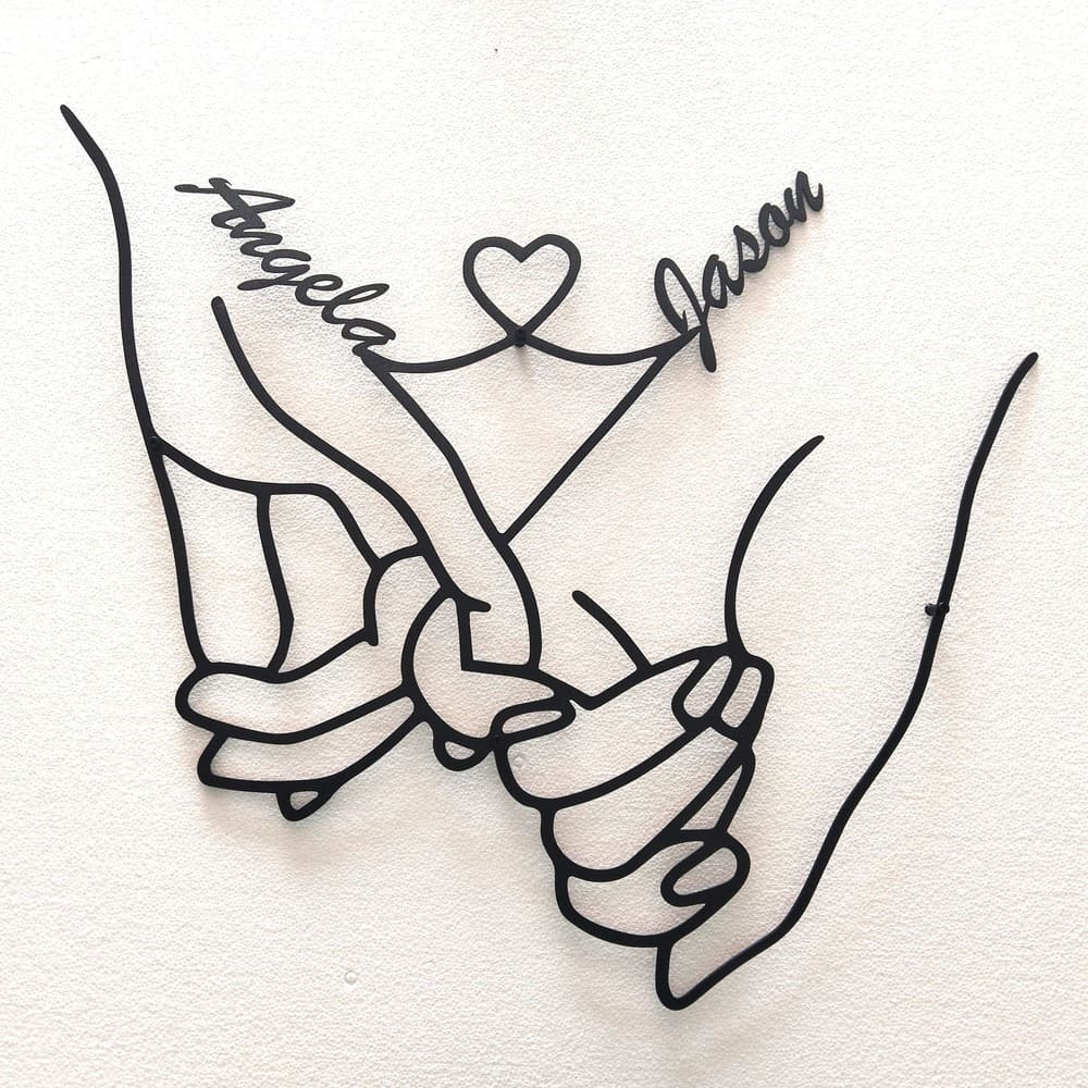 Personalized metal wall art featuring intertwined hands with the names Angela and Jason connected by a heart design.
