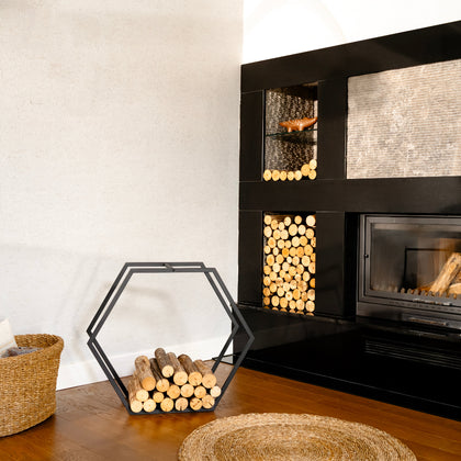 Modern fireplace with stacked firewood and a portable hexagonal firewood rack in a room