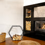 Modern fireplace with stacked firewood and a portable hexagonal firewood rack in a room