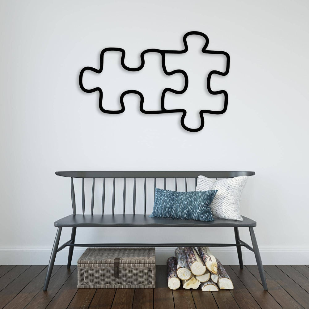 wo connected puzzle piece metal wall art in black, placed above a modern gray bench with pillows and logs beneath, creating a minimalistic decor
