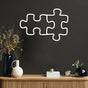 Two connected white puzzle piece metal wall art placed above a wooden console table with vases and modern decor items, adding a clean and contemporary touch.