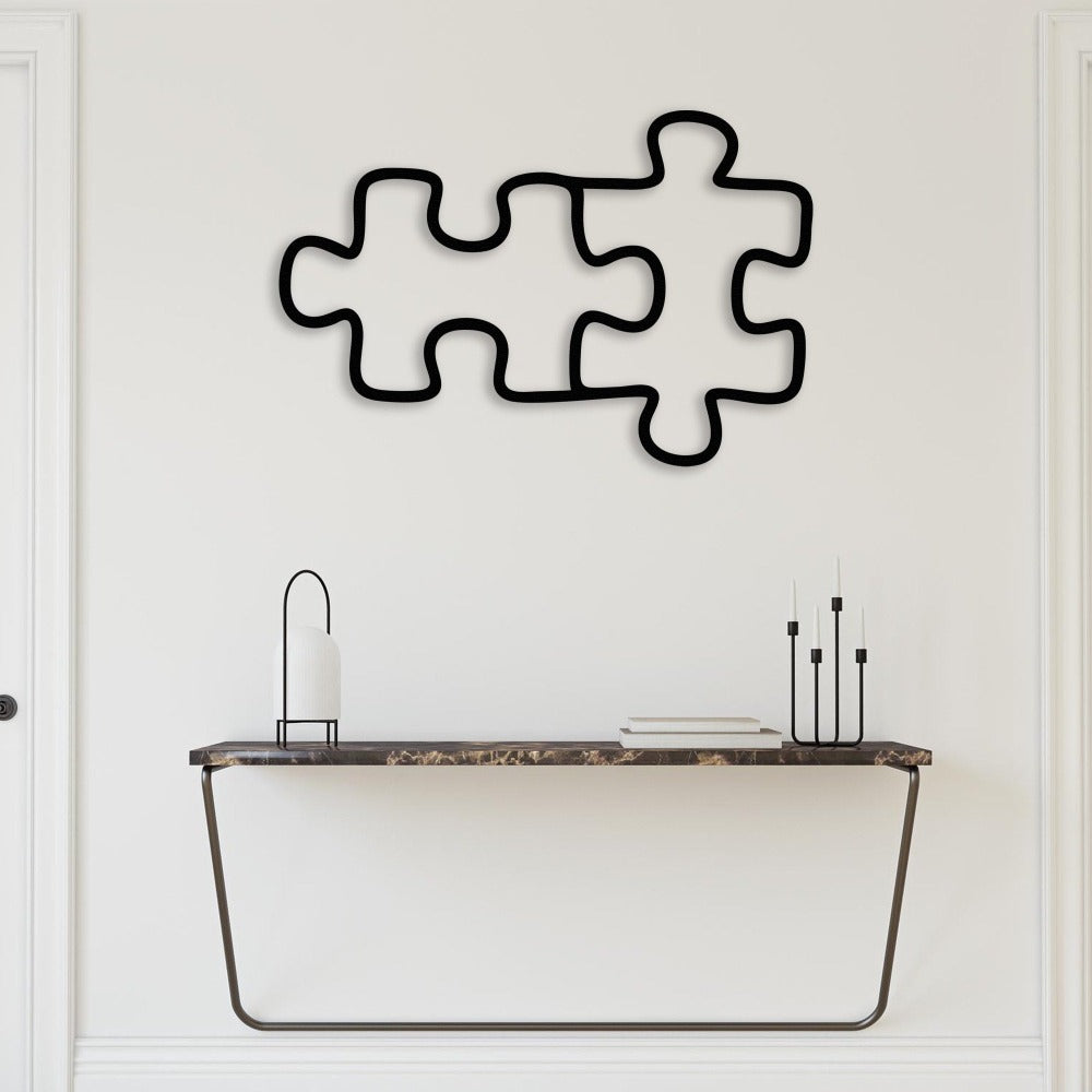 Two black puzzle piece wall art placed above a sleek marble console table with modern decor accents, blending simplicity with elegance.