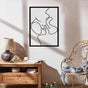 A cozy corner with a metal wall art of an abstract romantic couple titled "Relationship Goals," placed above a rustic wooden console with natural decor elements and candles.