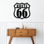 Route 66 black metal wall art mounted on a white wall above a mid-century modern wooden console table decorated with minimalist pottery and stacked books, creating a clean and iconic interior aesthetic.