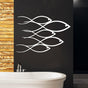 Modern white metal wall art featuring a school of fish design displayed on a dark wall above a freestanding bathtub with wooden panel accents.