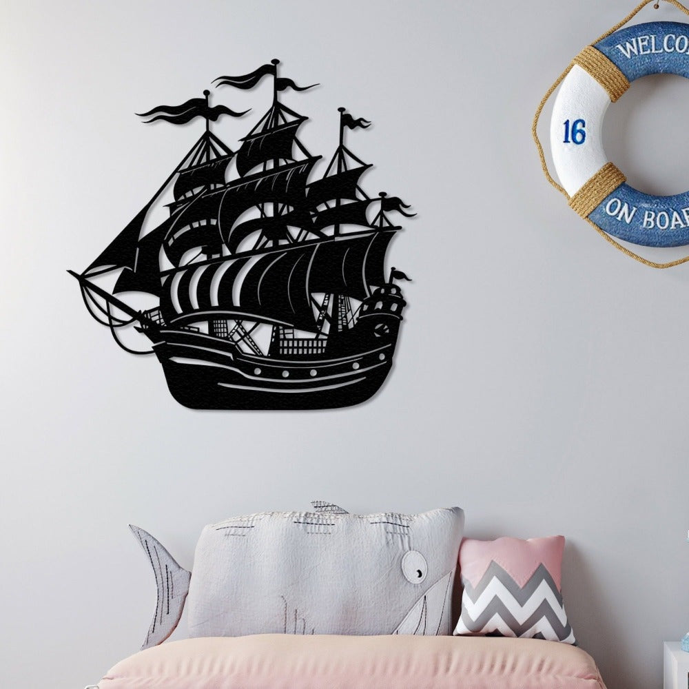 Black metal wall art of a sailing ship displayed on a white wall, styled with a nautical theme, featuring a "Welcome On Board" lifebuoy and decorative pillows.