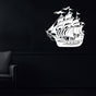 White metal ship wall art showcasing an intricately designed sailing vessel with masts and flags, mounted on a dark black wall in a sophisticated setting with a modern black armchair.