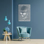 White skull-themed wall art with abstract wavy lines displayed on a blue wall, above a light blue armchair. Decor includes a side table with blue flowers and pendant lights.