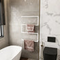 Wall-mounted towel holder on light grey tiles, neatly displaying pink towels in a modern bathroom.