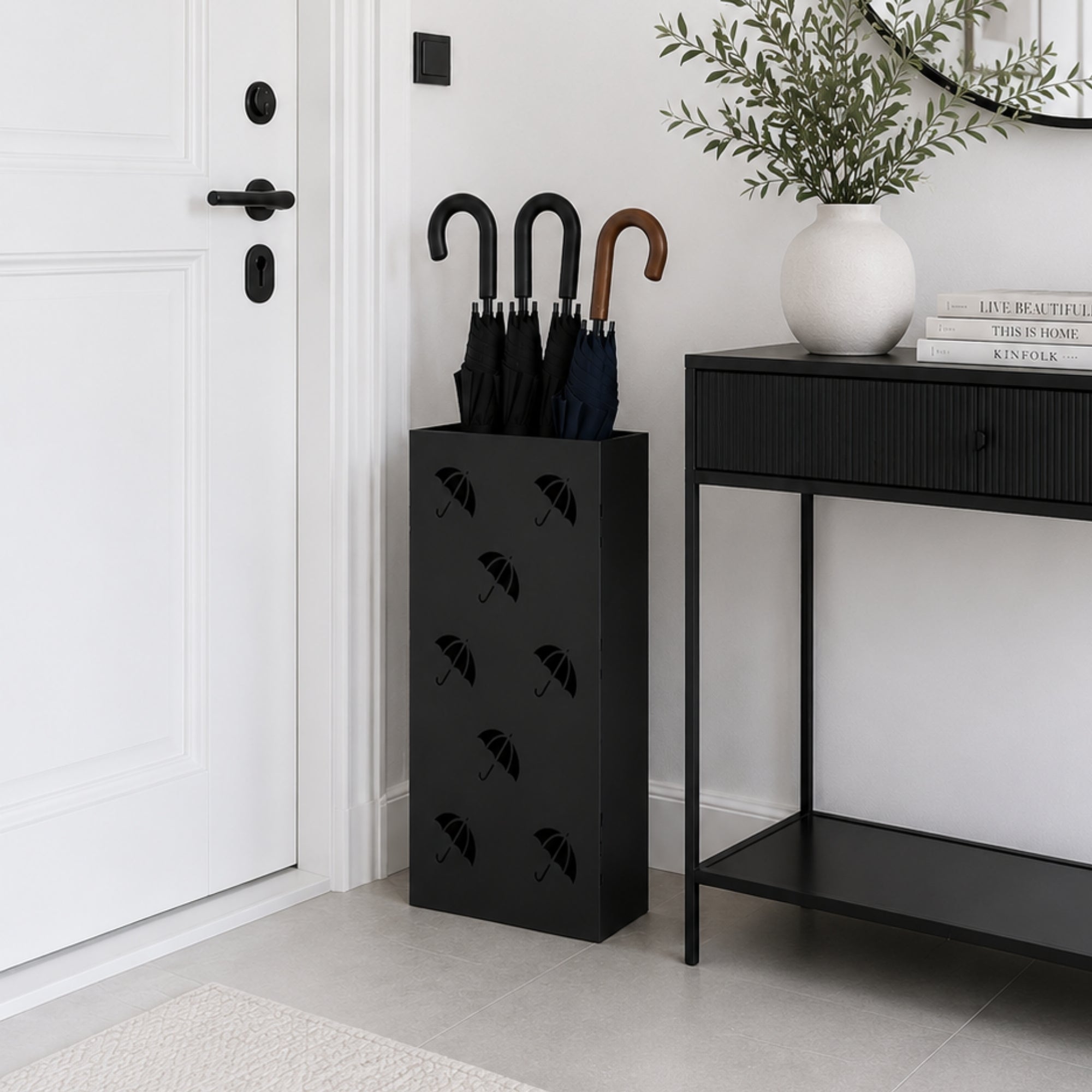 Tall black metal umbrella stand with multi-umbrella pattern beside console table in modern hallway