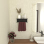  A black wall-mounted towel holder with a shelf, styled with decorative items and a red towel, adding functionality and elegance to a bathroom. 