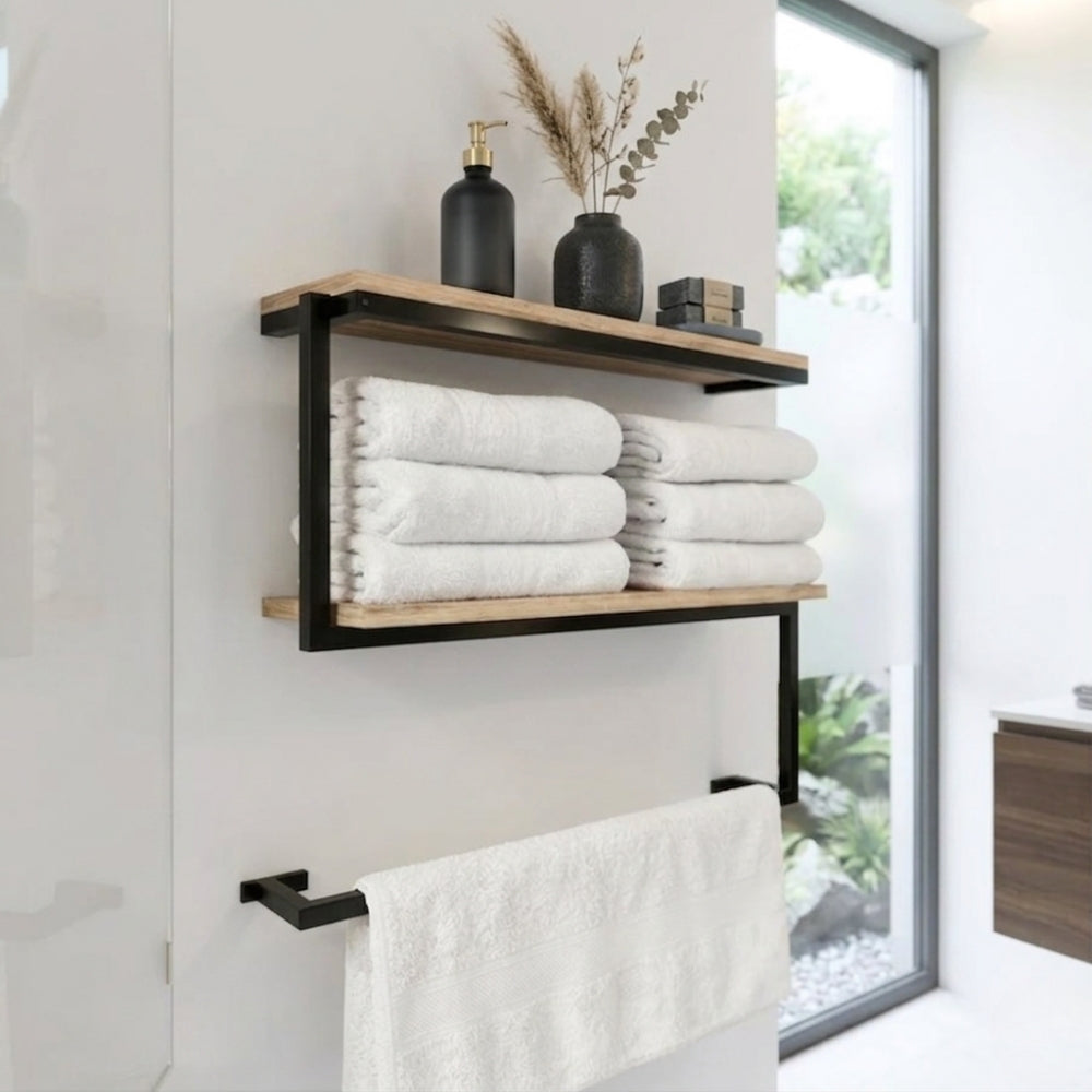 Black wall mounted 2-tier towel shelf with towel bar holding folded white towels and bathroom decor.
