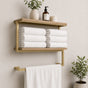Gold wall mounted 2-tier towel shelf with towel bar holding folded towels and bathroom decor.