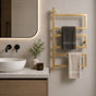 Gold wall mounted 3-tier towel rack holding gray and cream towels beside a modern bathroom vanity.