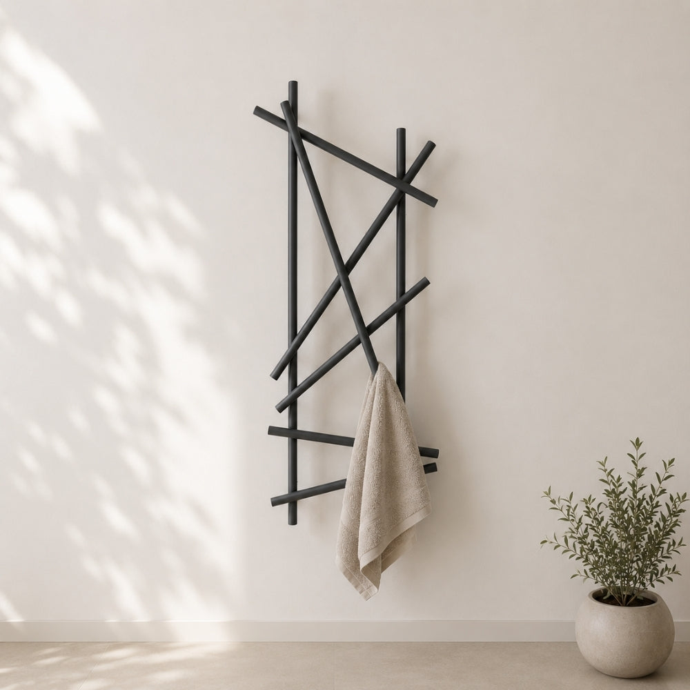 Black wall mounted branch towel rack holding a beige towel on a light bathroom wall.