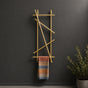 Gold wall mounted branch towel rack and coat rack holding a patterned towel on a dark wall.