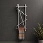 Satin nickel wall mounted branch towel rack and coat rack holding a patterned towel on a dark wall.