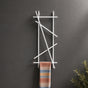 White wall mounted branch towel rack and coat rack holding a patterned towel on a dark wall.