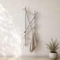 Satin nickel wall mounted branch towel rack holding a beige towel on a light bathroom wall.