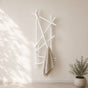 White wall mounted branch towel rack holding a beige towel on a light bathroom wall.