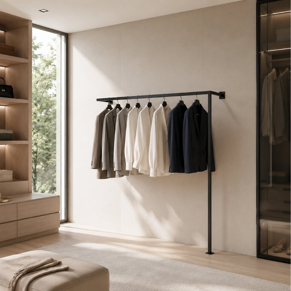 Black wall mounted clothing rack holding shirts and jackets in a modern bedroom.