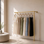 Gold wall mounted clothing rack holding dresses in a bright dressing room.