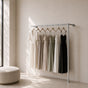 Satin nickel wall mounted clothing rack holding dresses in a bright dressing room.