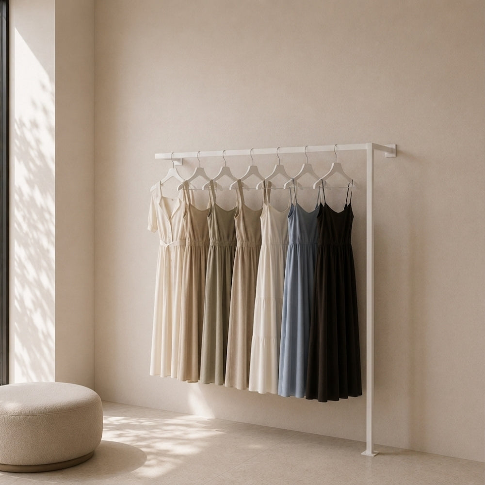 White wall mounted clothing rack holding dresses in a bright dressing room.