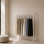White wall mounted clothing rack holding dresses in a bright dressing room.