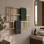 Gold wall mounted geometric towel rack holding green and gray towels beside a modern bathroom vanity.