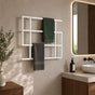 White wall mounted geometric towel rack holding green and gray towels beside a modern bathroom vanity.