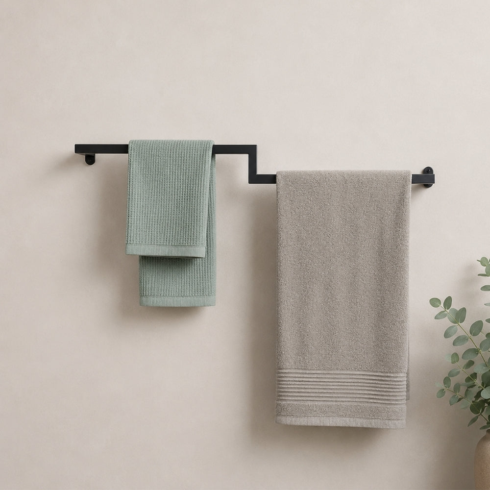 Black wall mounted offset double towel bar holding mint and gray towels on a bathroom wall.