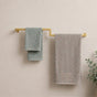 Gold wall mounted offset double towel bar holding mint and gray towels on a bathroom wall.