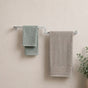 Satin nickel wall mounted offset double towel bar holding mint and gray towels on a bathroom wall.